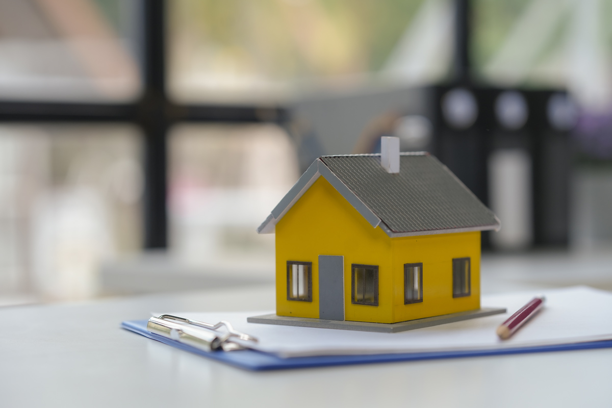 Miniature yellow house on paperwork with pen and red pencil, representing Home Loan Top Up process