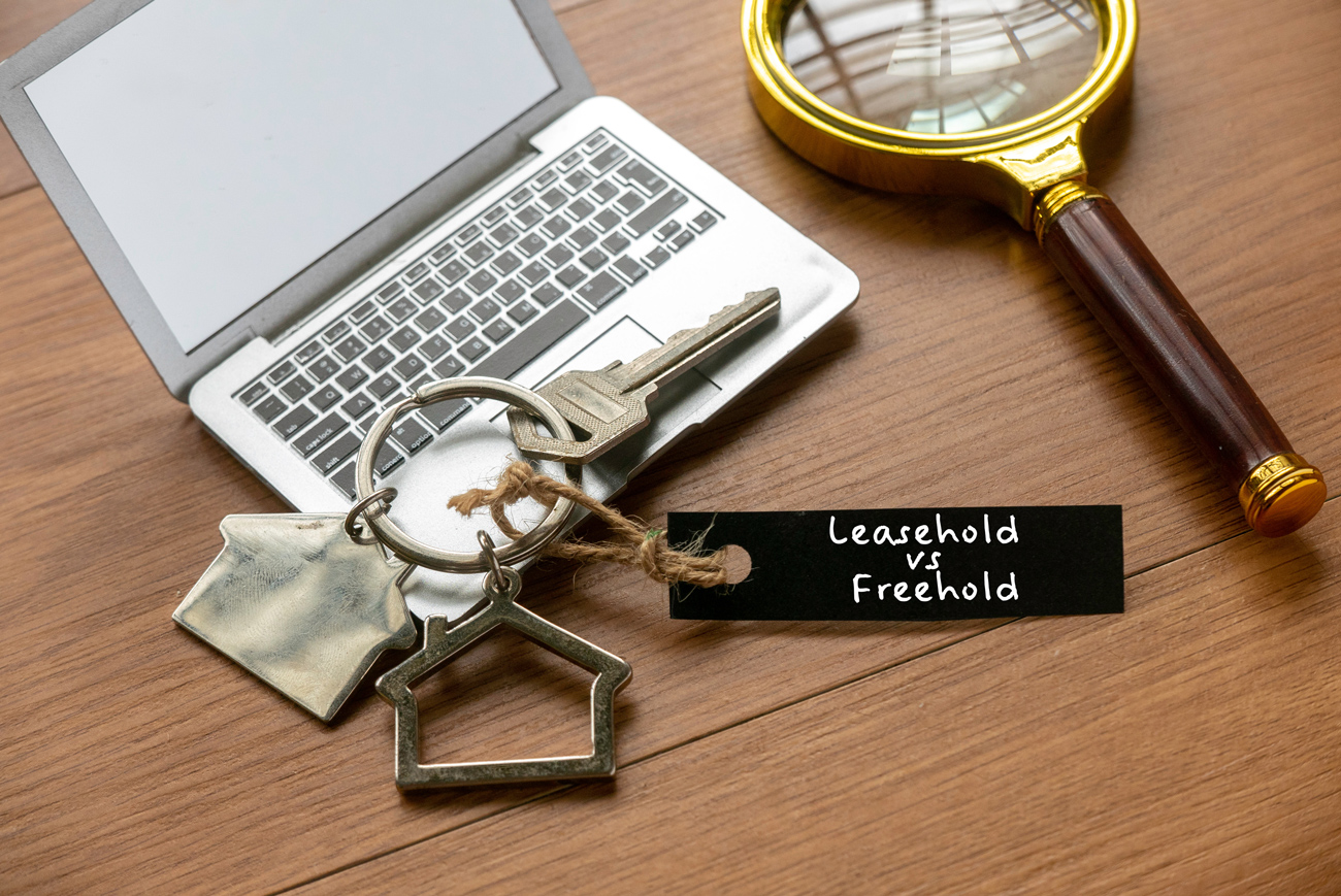 House key on wooden table representing freehold vs leasehold concept