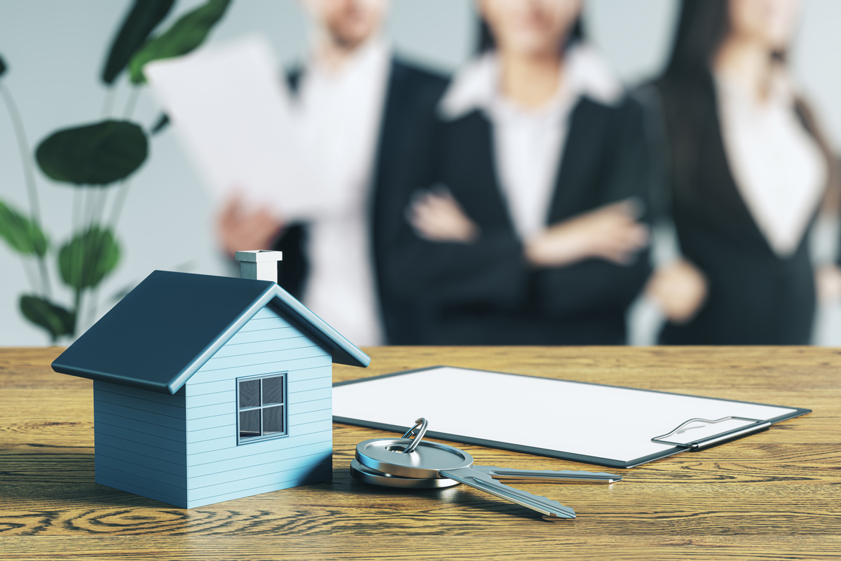 Home Loan Top Up concept with house paperwork and keys on wooden office desk people standing in background