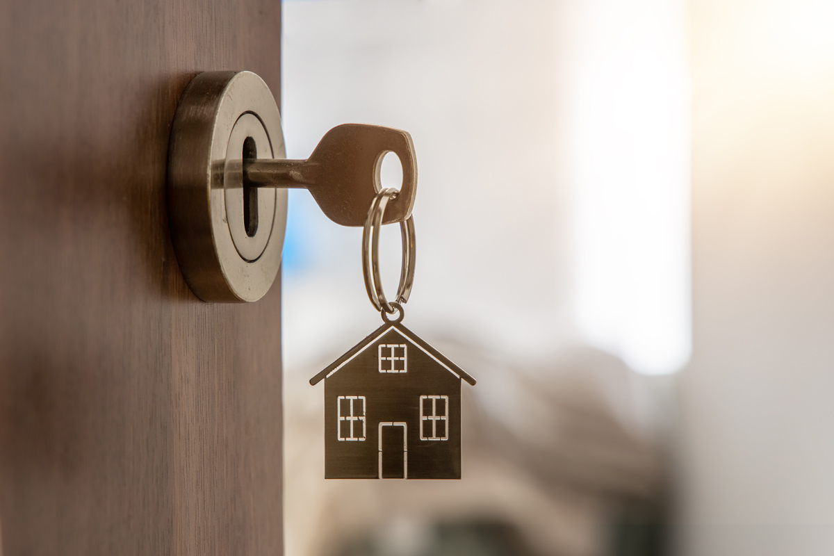 Open door with key and home-shaped keychain, symbolizing new home ownership