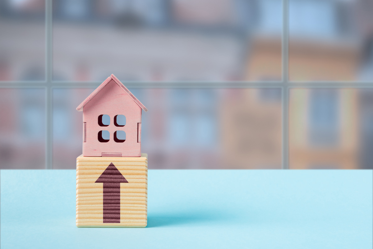 Pink house on top of a wooden block with an upward arrow symbolizing top up loan