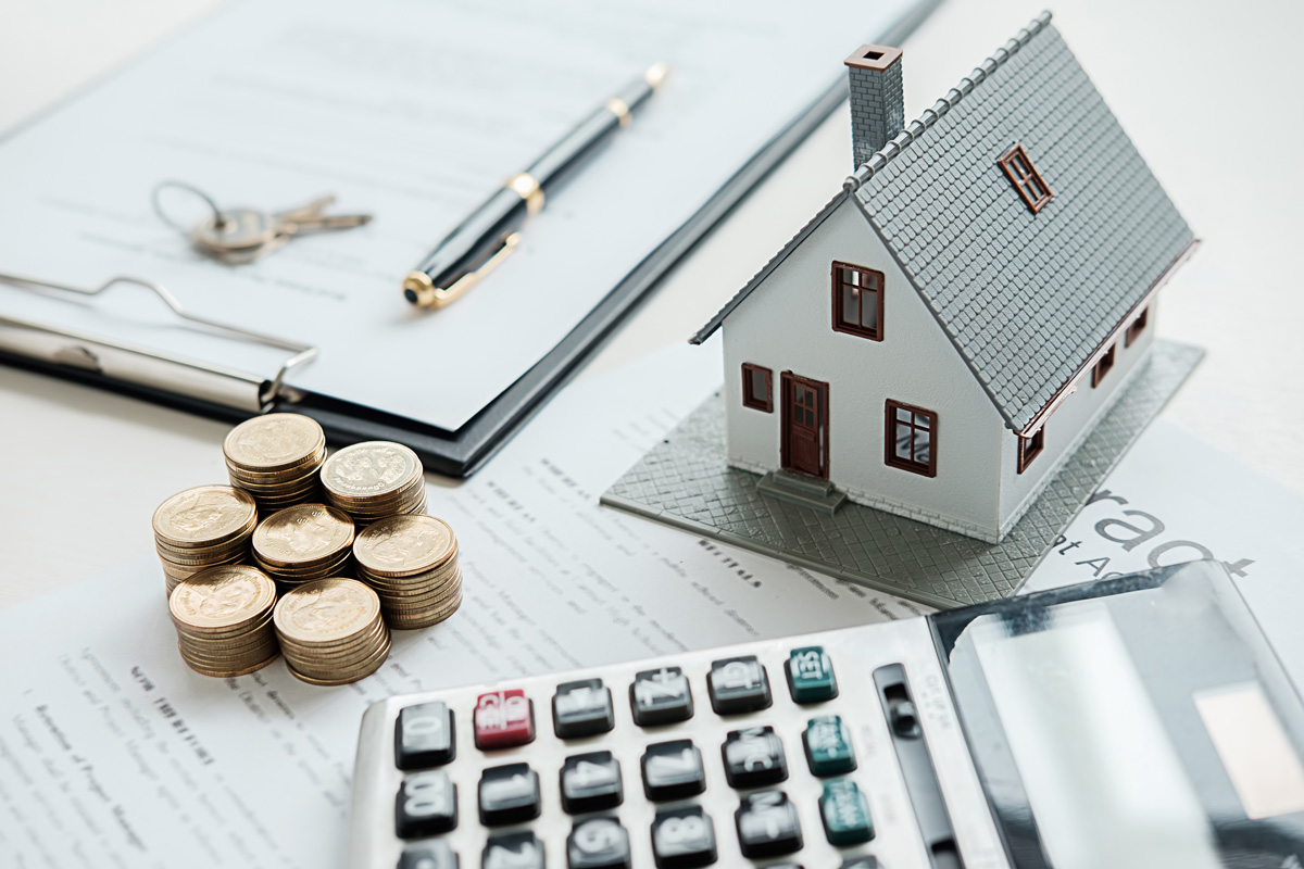Agent discussing home loan with customer featuring a house model in the background.